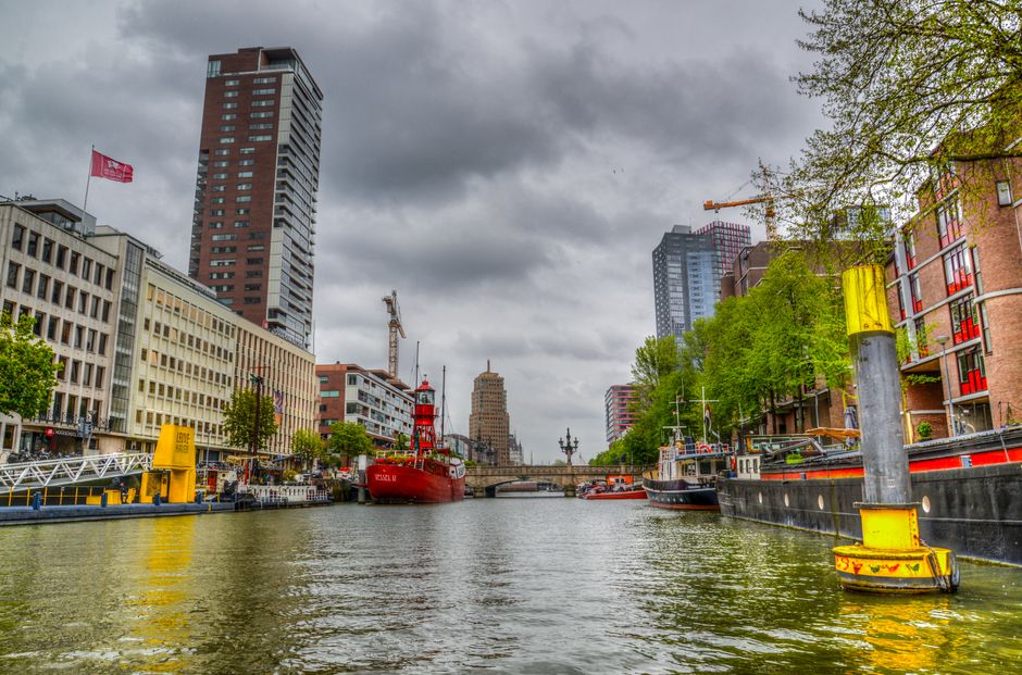 Vibrant city scene of Rotterdam with modern architecture along a bustling waterway.