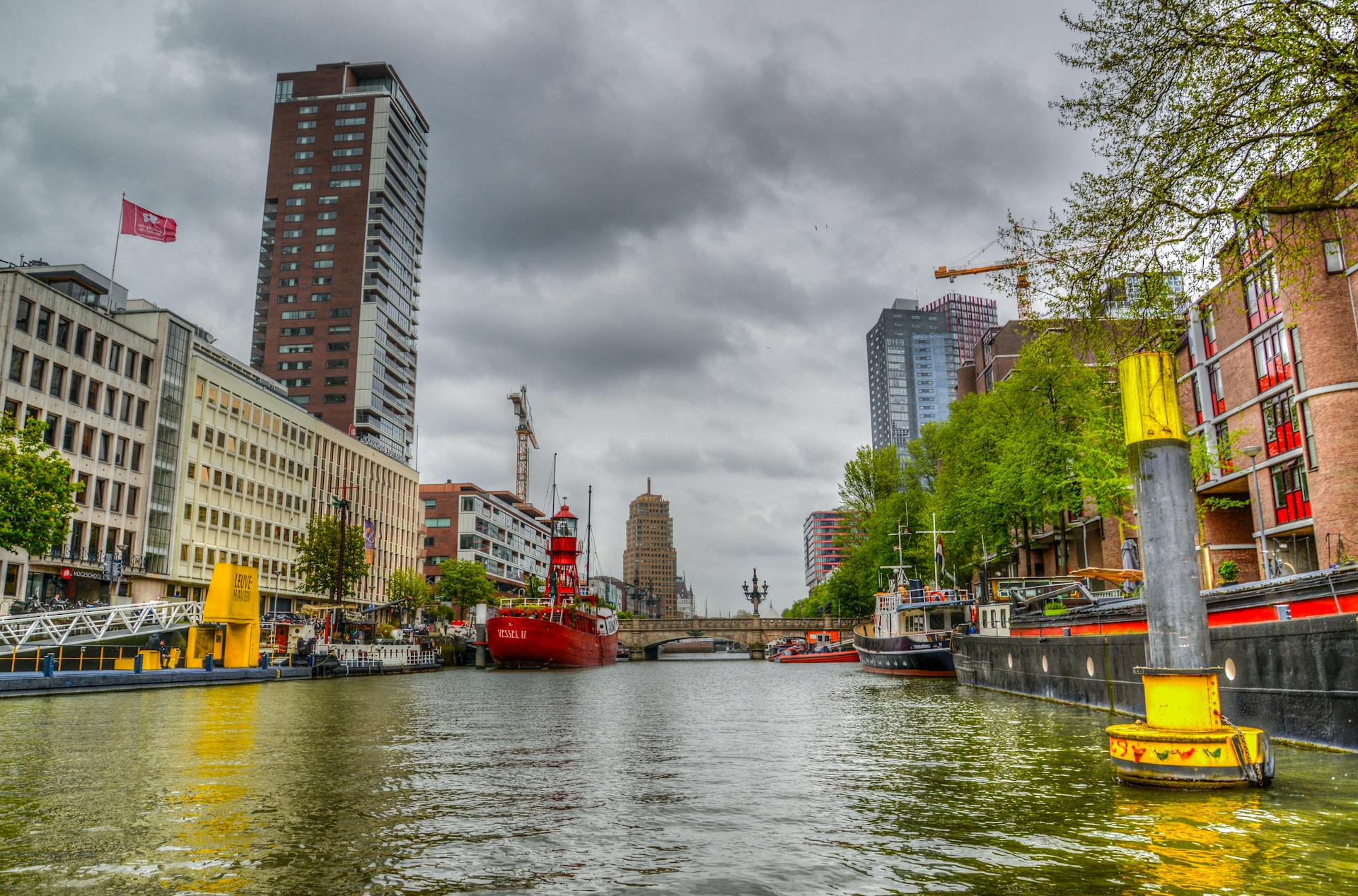 Vibrant city scene of Rotterdam with modern architecture along a bustling waterway.