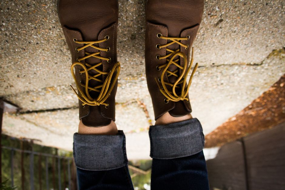Close-up of brown leather boots with yellow laces on urban pavement. Fashionable style.
