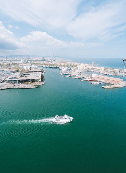 Free Aerial shot of Barcelona harbor showcasing boats, buildings, and the sea. Stock Photo