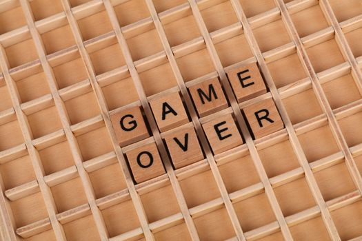 Close-up of wooden Scrabble tiles spelling 'Game Over' on a letter board.