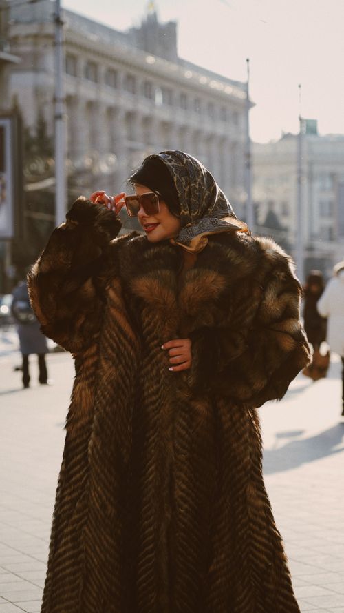 Free Stylish woman wearing fur coat and headscarf with sunglasses on a city street. Stock Photo