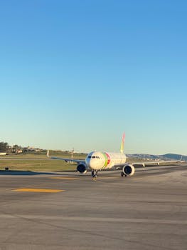 A commercial airplane on the runway against a clear blue sky, ready for takeoff.