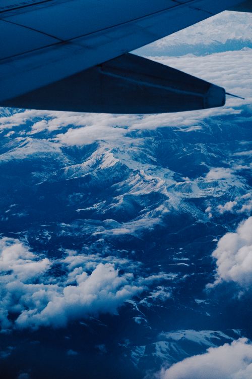 Free Stunning aerial view of snow-capped mountains seen from a plane window. Stock Photo
