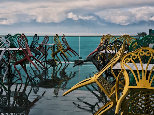 Free Armchairs Tilted on Tables on a Wooden Deck Near a Body of Water Stock Photo