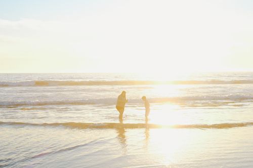 Free A woman and child enjoy a sunny day at the beach, standing in the serene waves. Stock Photo