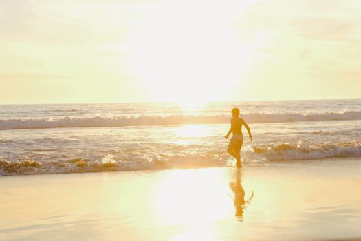 A child plays by the ocean at sunset, creating a serene seaside reflection.