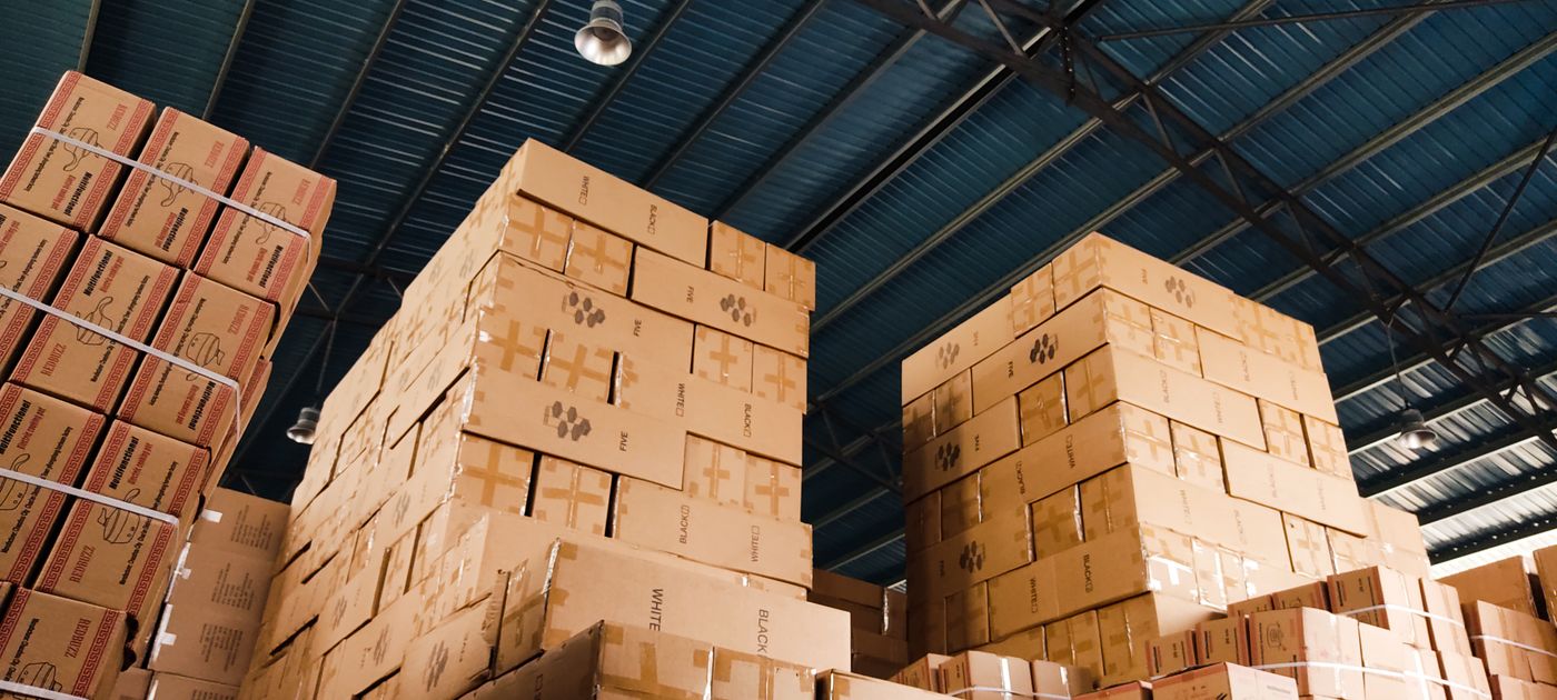 High stacks of cardboard cartons in a warehouse — corrugated board is the main pest vector in a fulfilment operation