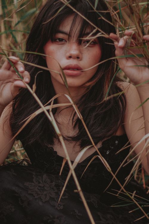 Free Intimate close-up portrait of a woman surrounded by grass, creating a mysterious and earthy mood. Stock Photo