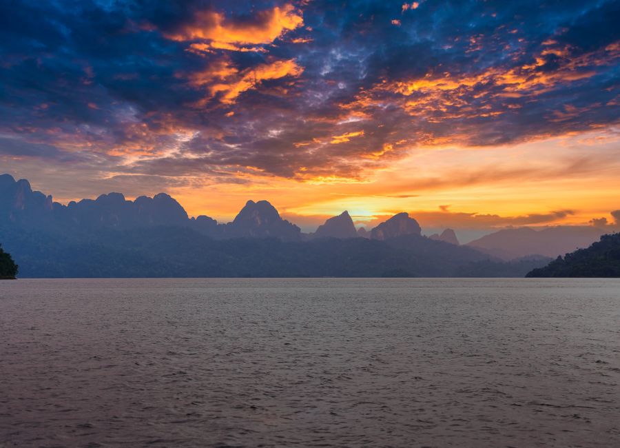 Stunning sunset view over Khao Sok's mountains and lake, Thailand.