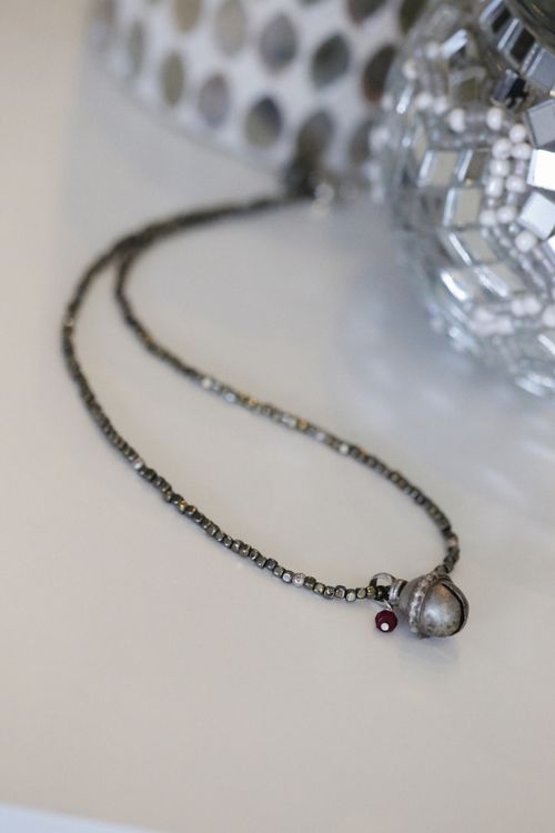 Free Close-up of a beaded chain necklace with gemstones on a reflective decorative surface. Stock Photo