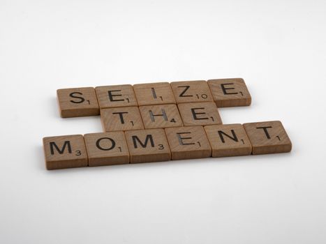 Inspirational phrase 'Seize the Moment' crafted in Scrabble-style wooden tiles on white background.