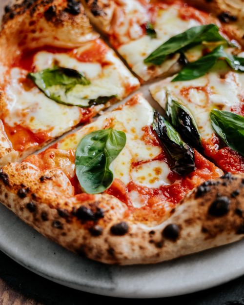 Free Close-up of a Neapolitan pizza with fresh basil leaves and melted cheese, perfect for food enthusiasts Stock Photo