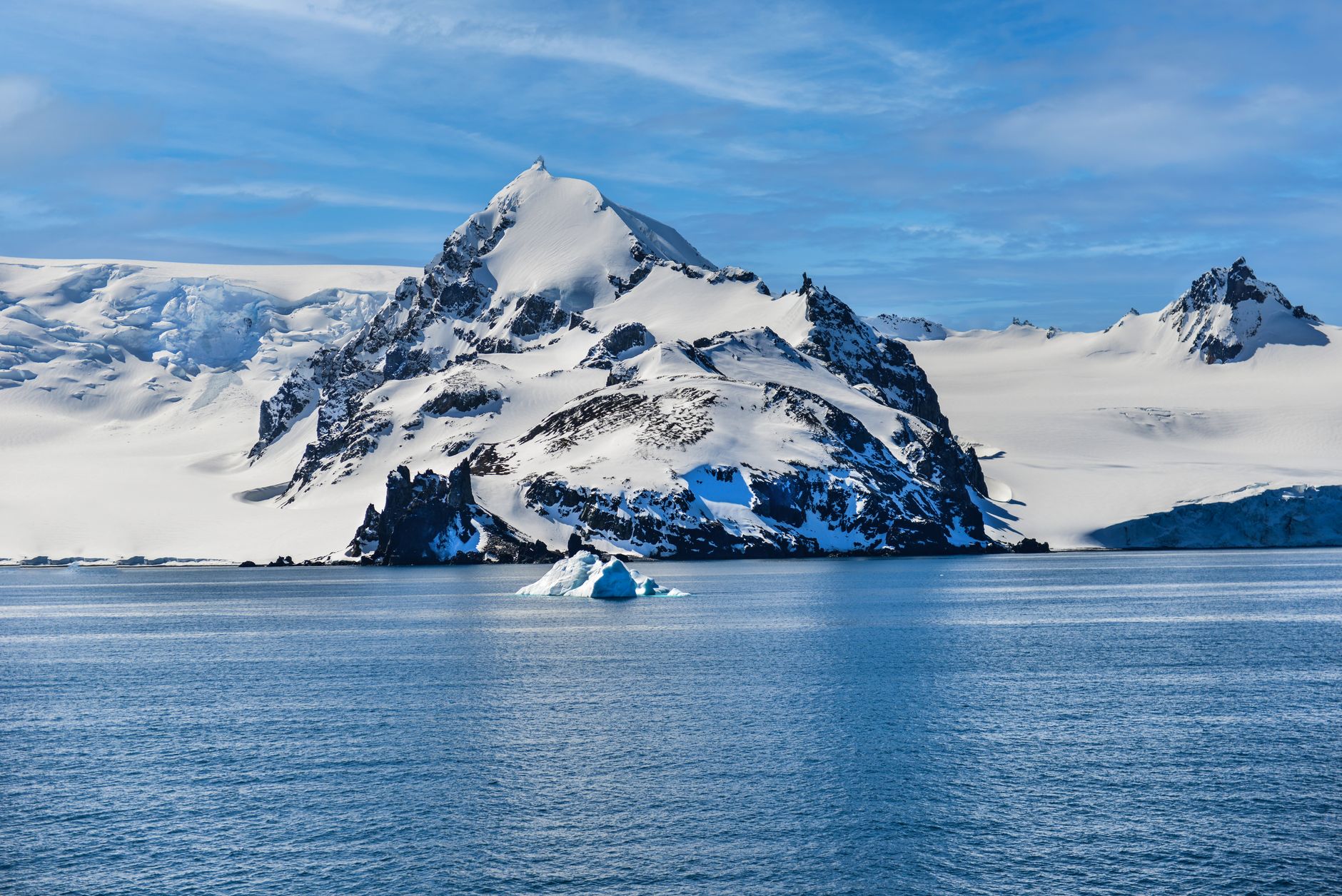 Stunning view of a snow-covered mountain and iceberg in Antarctica's icy waters.