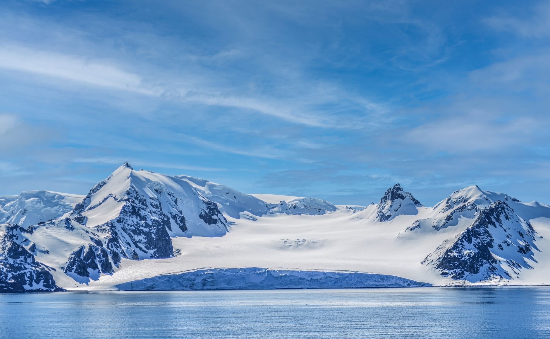 Breathtaking view of rugged snowy mountains under a clear blue sky in Antarctica.