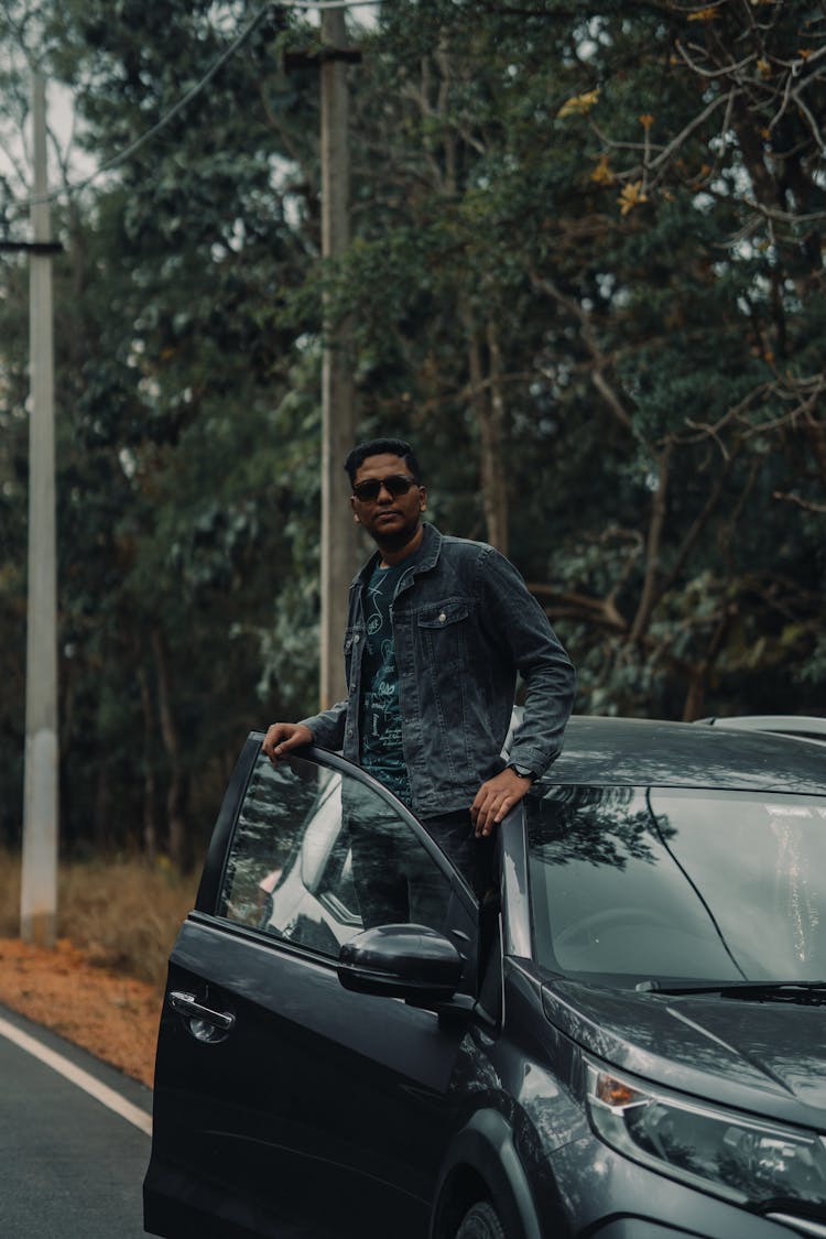 Man In Black Jacket Standing Inside A Car 