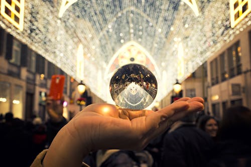 Person Holding Round Silver-colored Accessory