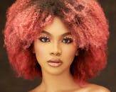 一位拥有粉色卷发、画着艺术妆容的女性的迷人肖像