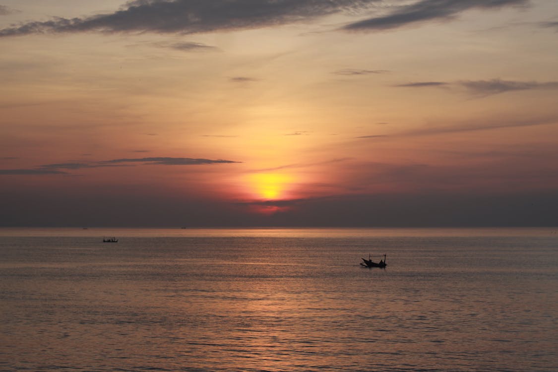 Silhouette of a Boat on Sea during Sunset