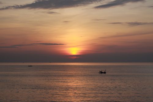 Free A calm sunset view over the ocean, featuring silhouettes of boats under a colorful sky. Stock Photo