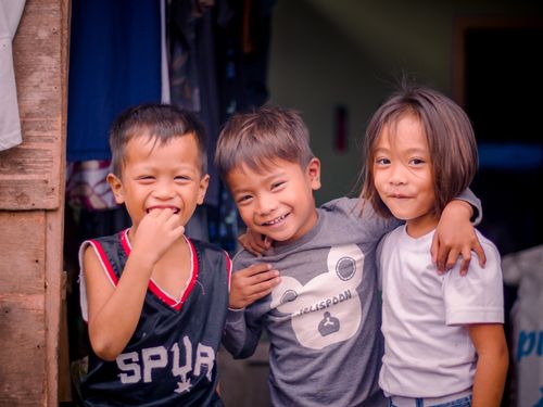 Free Three smiling children enjoy a happy moment together outside, showcasing friendship and joy. Stock Photo