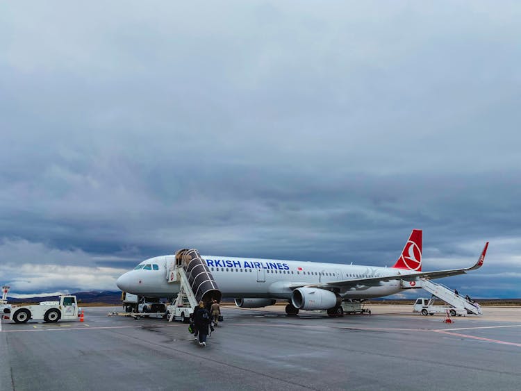 People Boarding An Airplane Parked On The Tarmac