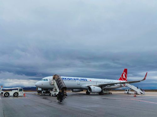 Free Turkish Airlines Airbus A321 on the tarmac with passengers boarding under a cloudy sky. Stock Photo