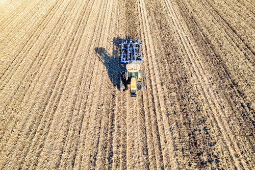 A Tractor on Brown Agricultural Land