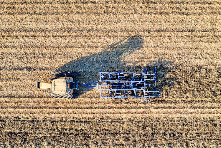 Blue Tractor Plowing On Brown Field