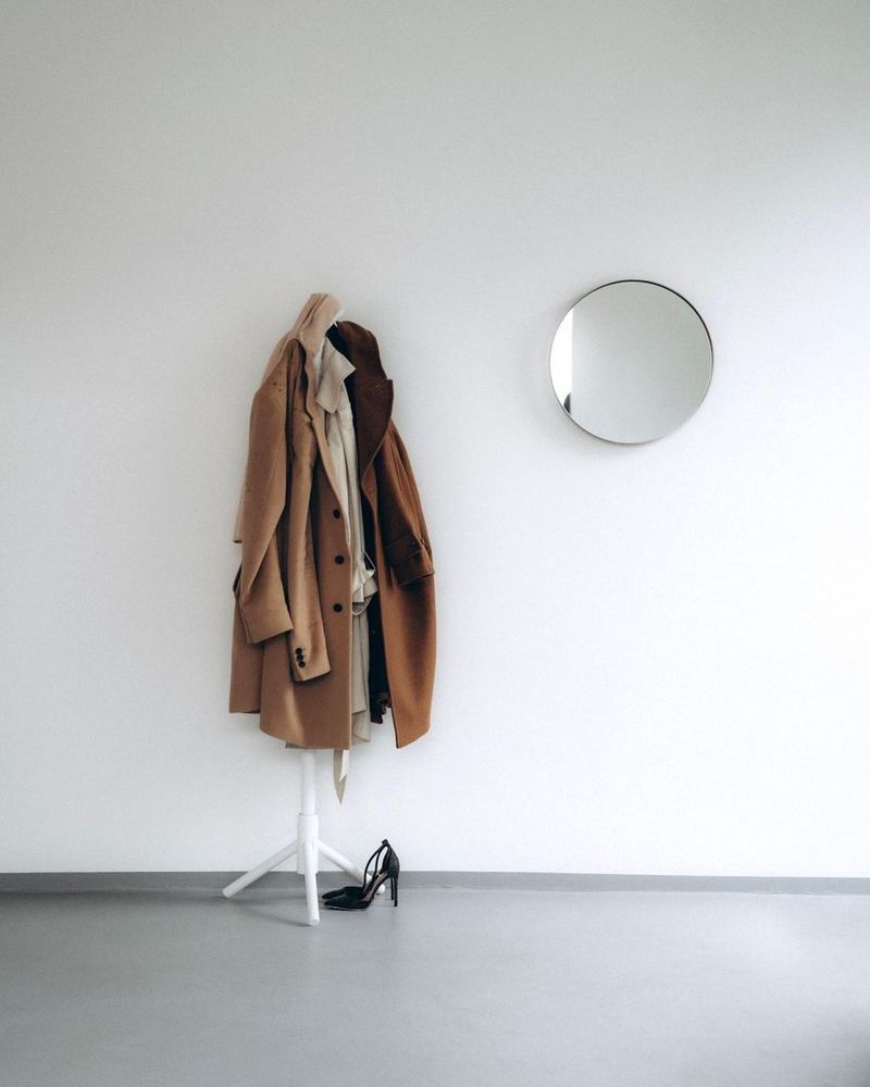 Modern minimalist entryway with a freestanding coat rack and round mirror