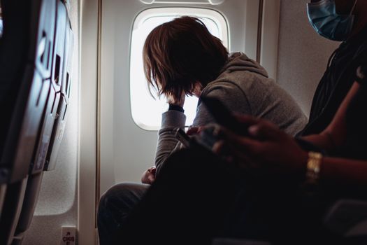 A passenger gazes out of an airplane window, reflecting on in-flight travel.