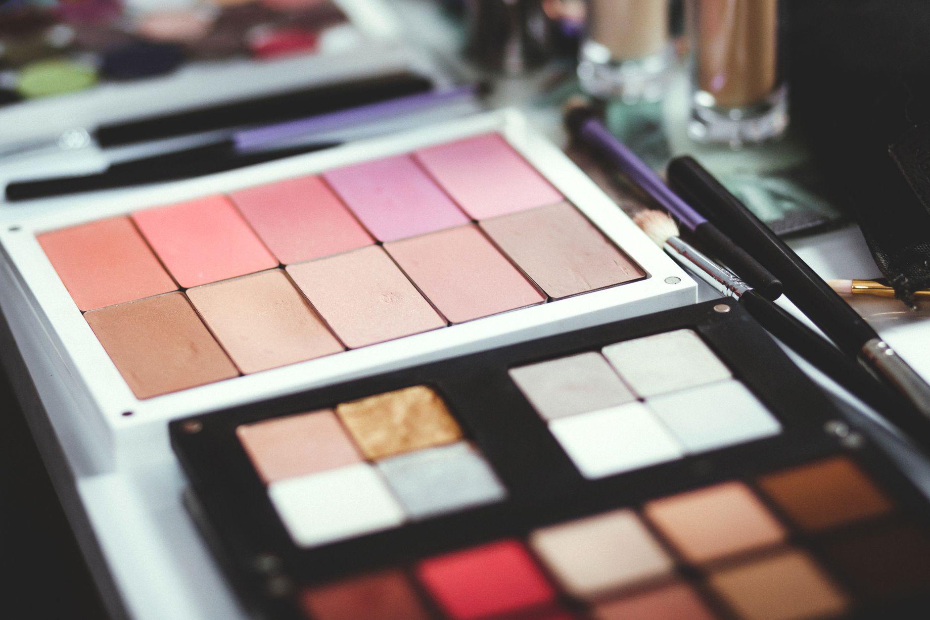 Close-up of colorful makeup palettes with brushes, perfect for beauty and fashion themes.