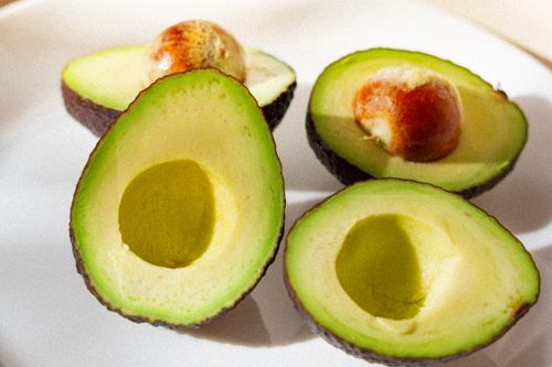 Free A close-up of ripe, sliced avocados arranged on a white plate. Stock Photo
