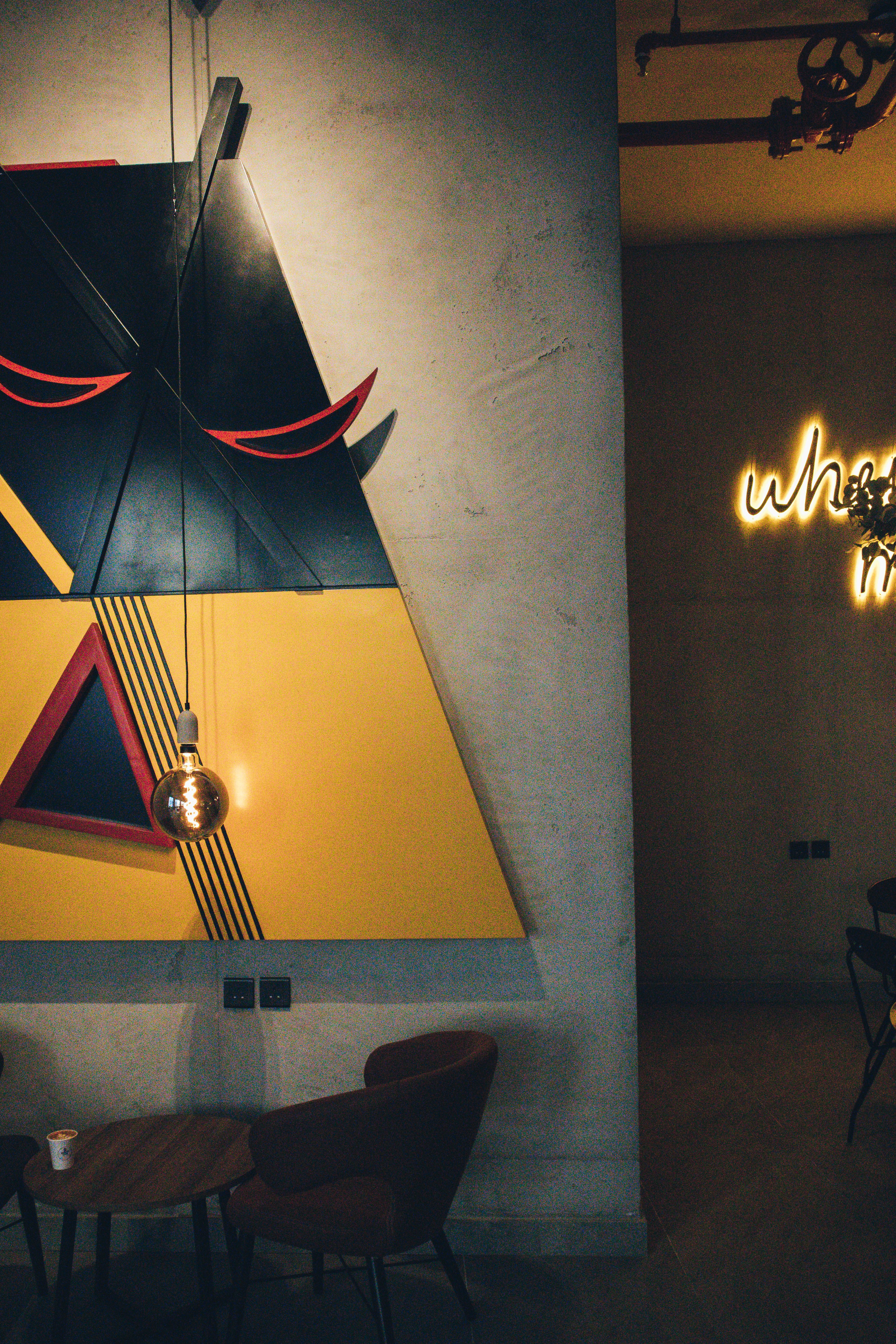 Visual of a modern café in Jeddah with artistic murals and moody lighting.