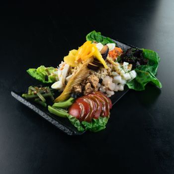 Vibrant Moroccan salad with a variety of fresh ingredients on a black plate.