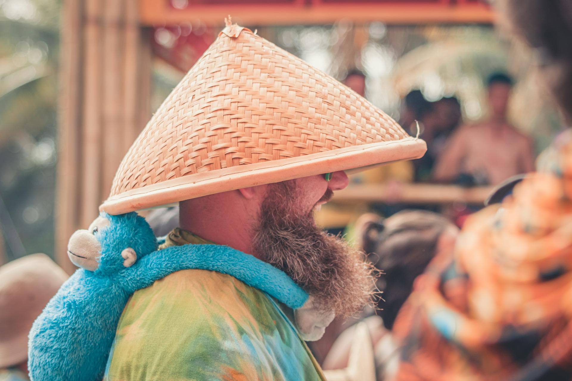 Side View of Man Wearing Brown Hat With Stuff Toy Monkey Hanging on His Shoulder