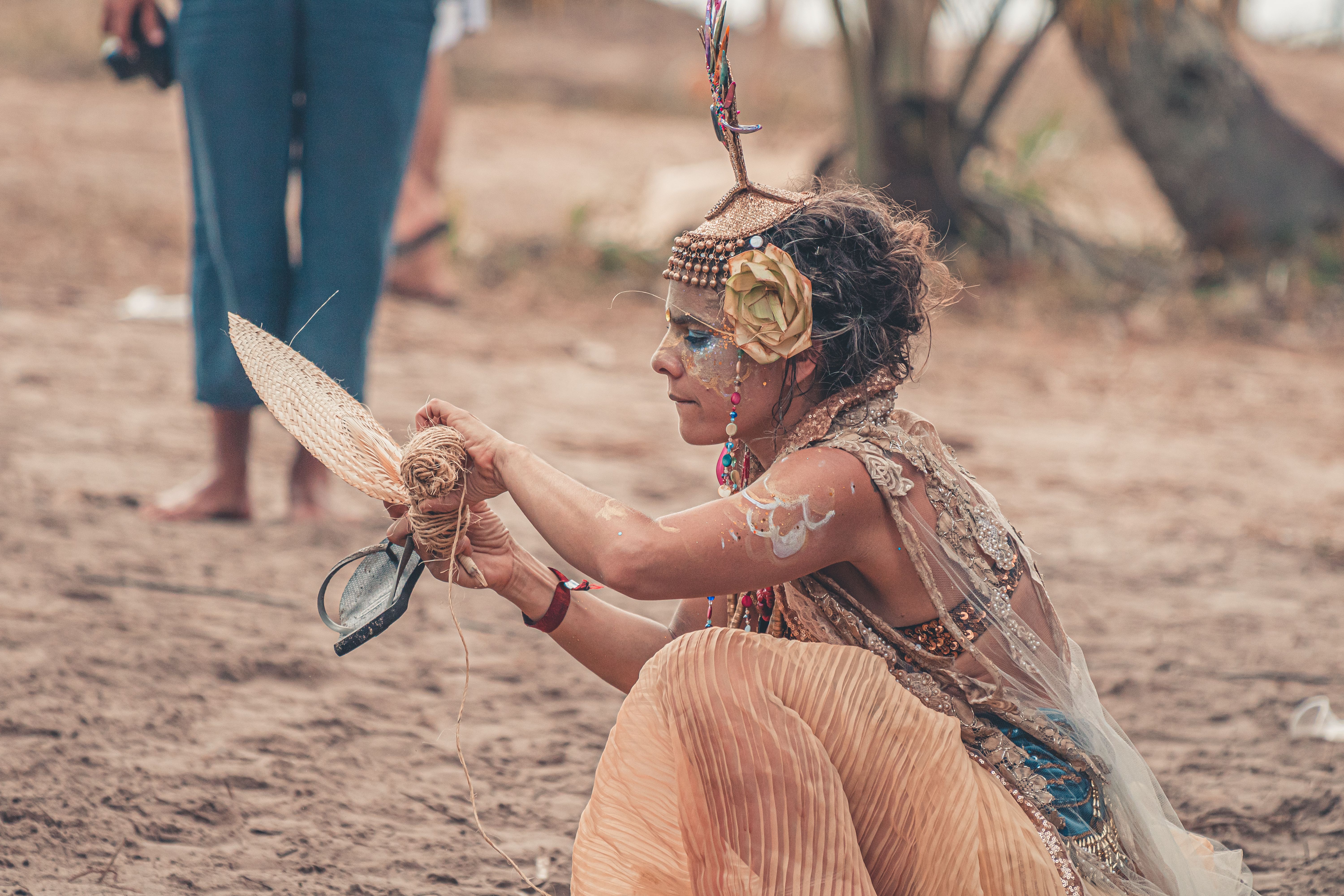 sand art activity for events egypt — A woman with face paint and traditional attire creates craft at an outdoor festival.