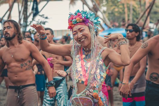 Exciting beach party with people dancing, enjoying music and colorful outfits.