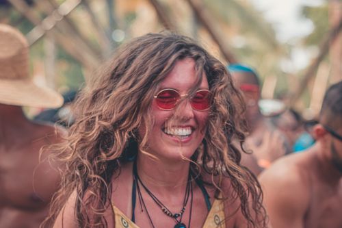 Free Smiling woman wearing red sunglasses at a lively outdoor festival in summer. Stock Photo
