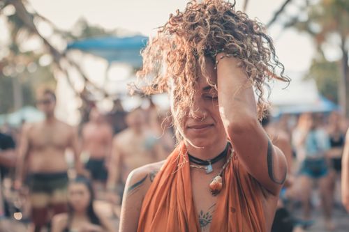 Free A young woman with curly hair enjoying an outdoor festival with friends in summer. Stock Photo