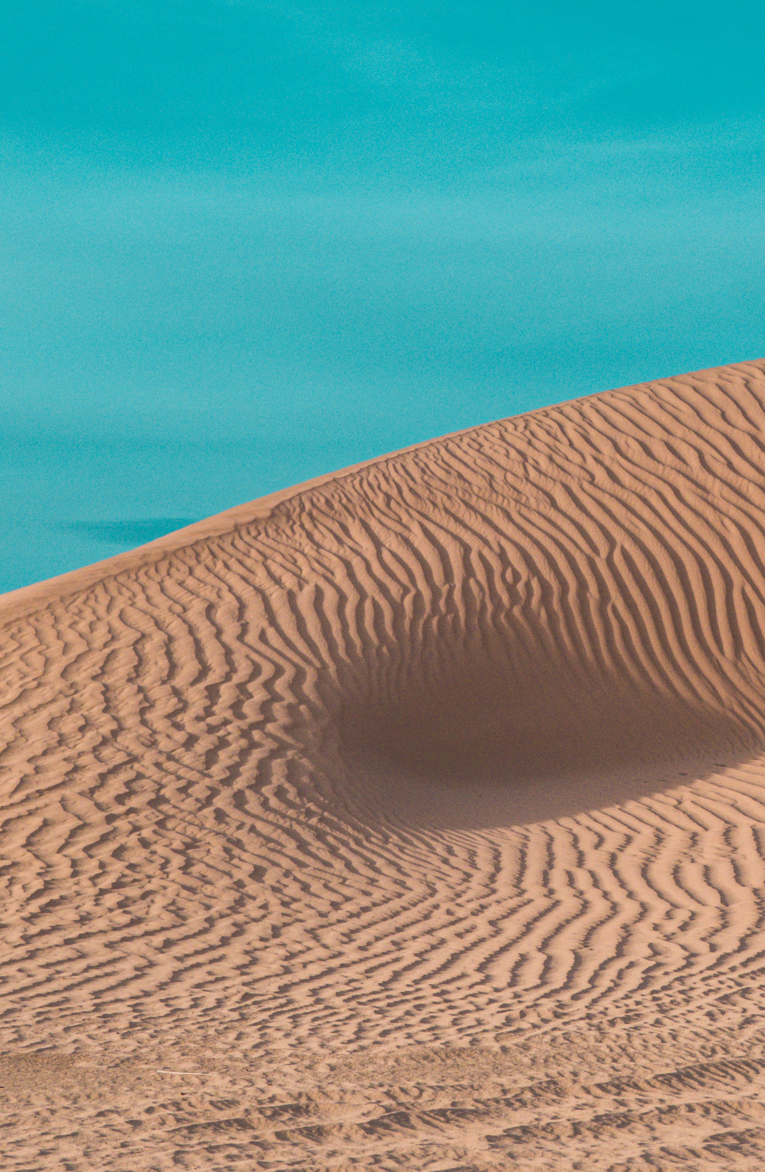 A scenic view of Algerian sand dunes against a vibrant blue sky, showcasing natural desert beauty.
