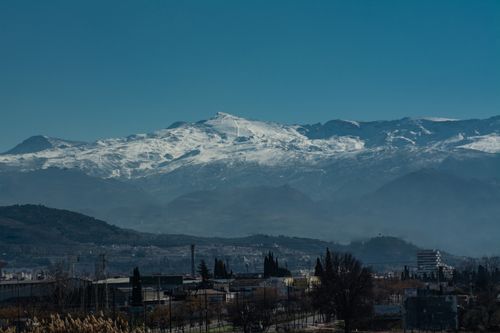 Free Beautiful mountain landscape with snow-capped peaks and a village below, ideal for nature and travel themes. Stock Photo