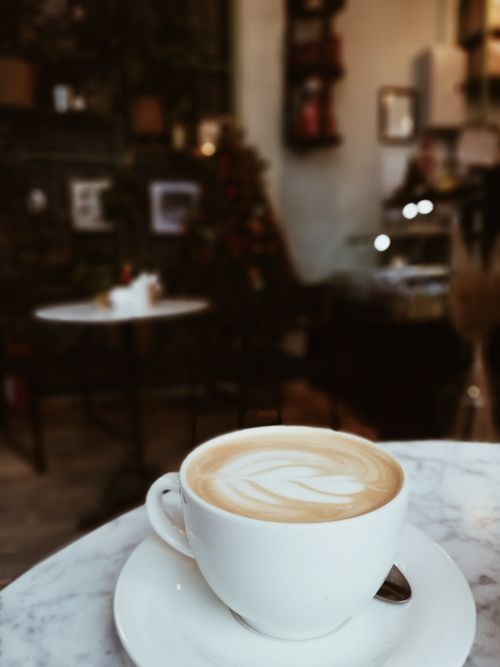 Free Warm cafe scene featuring a creamy latte with beautiful latte art, perfect for coffee lovers. Stock Photo