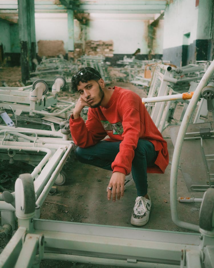 A Man In Red Sweater Posing Inside An Old Factory