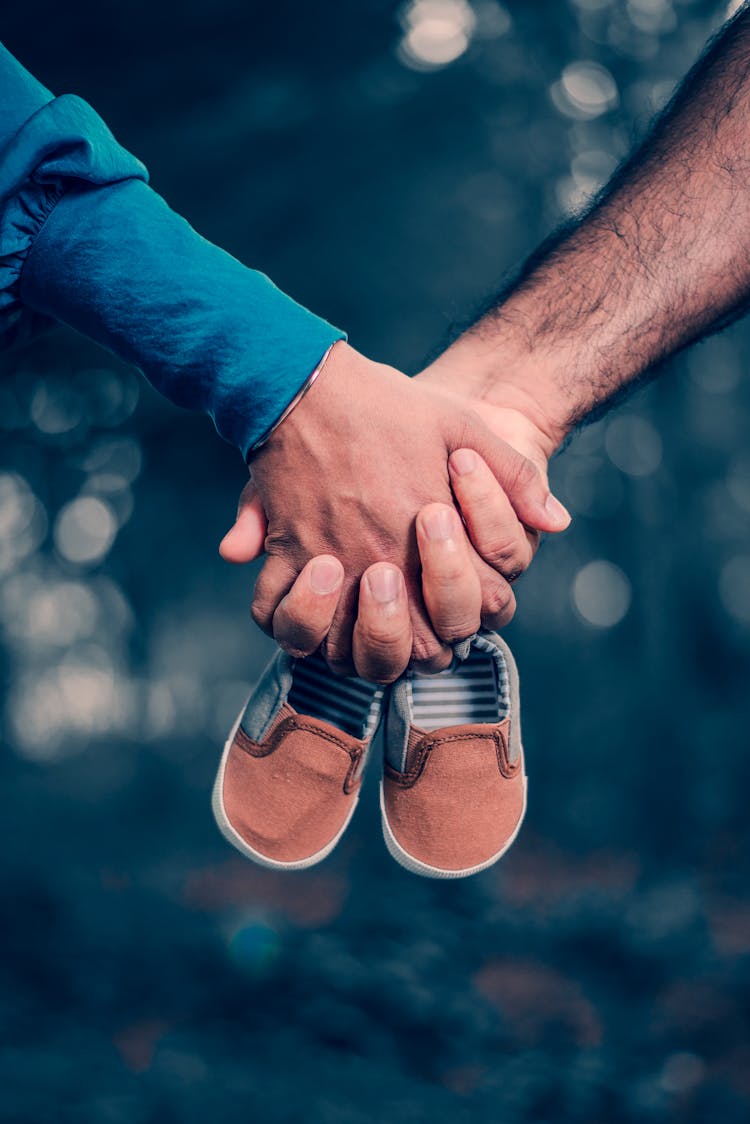 A Couple Holding Brown Baby Shoes