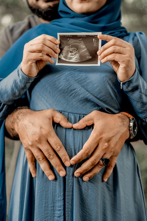 A Pregnant Woman in Blue Dress Holding an Ultrasound 