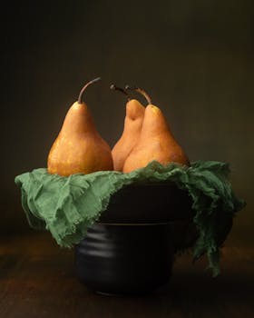 Artistic still life of ripe pears in a dark bowl with soft lighting.