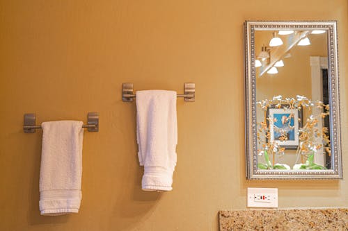 White Bath Towels on Stainless Steel Towel Holder Beside a Mirror