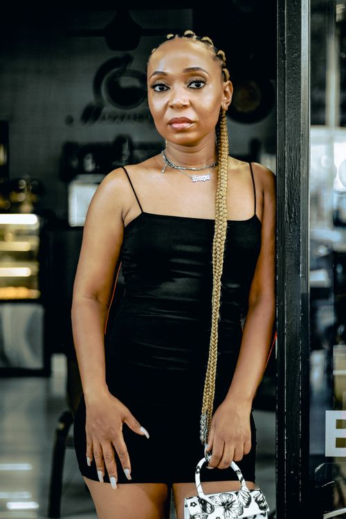 Free Trendy woman in a black dress posing indoors, exuding confidence and style. Stock Photo