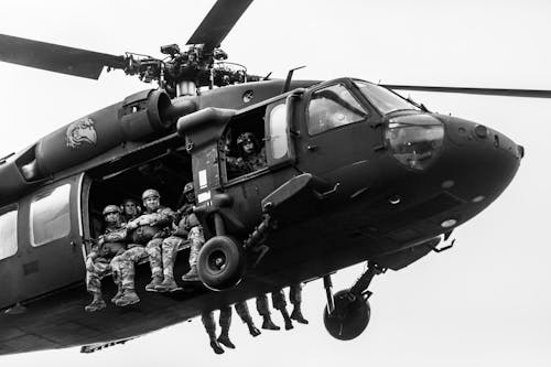 A Grayscale of Soldiers Riding a Utility Helicopter